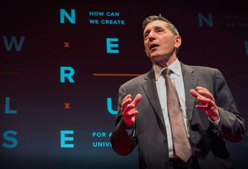 A man in suit and tie speaking on stage.