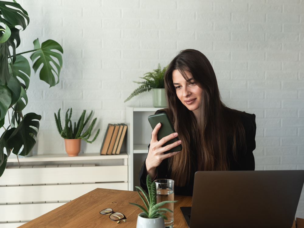 A woman sitting at a table looking at her phone.