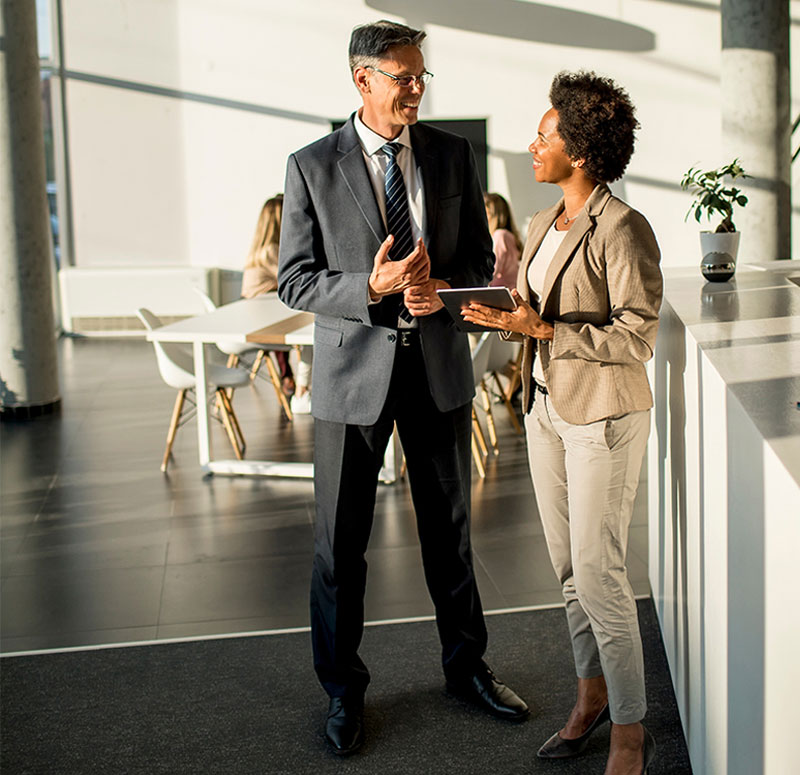 Two people standing in a room talking to each other.