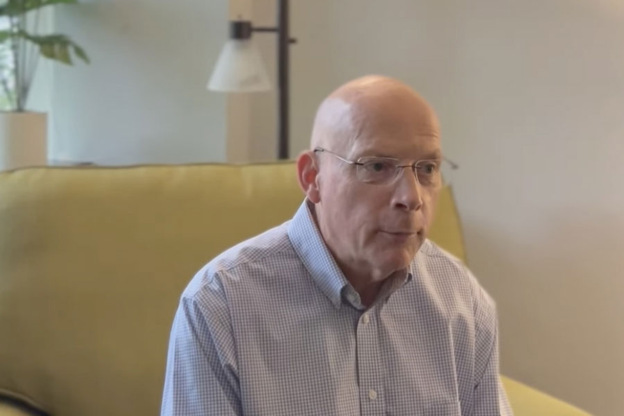 A man sitting on top of a couch in front of a wall.