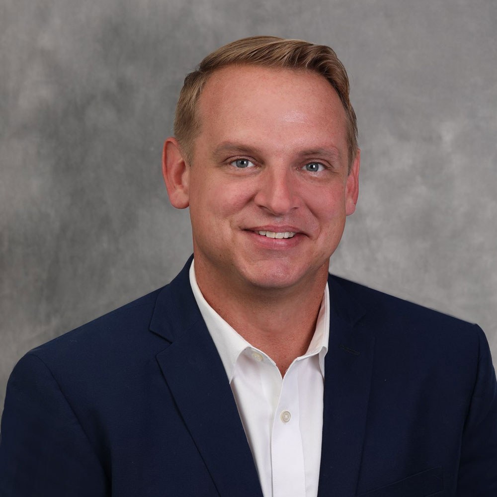 A man in a suit and tie smiling for the camera.