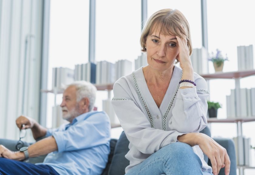 A woman sitting next to another man in front of a window.