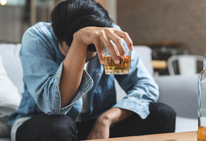 A person sitting down with a glass of alcohol.