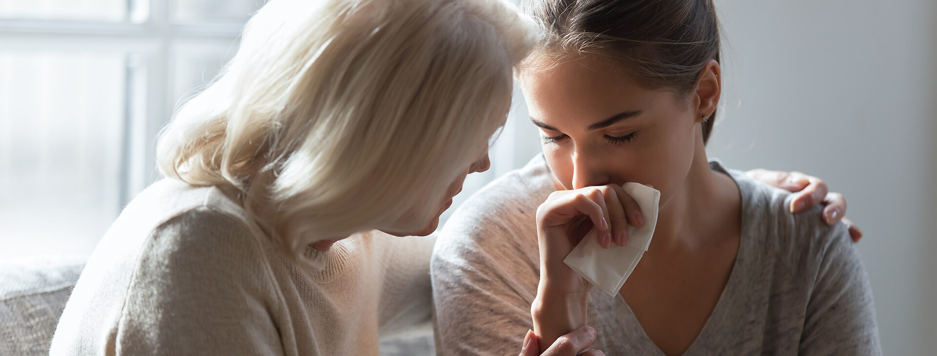 Two women are talking and one is holding a tissue.