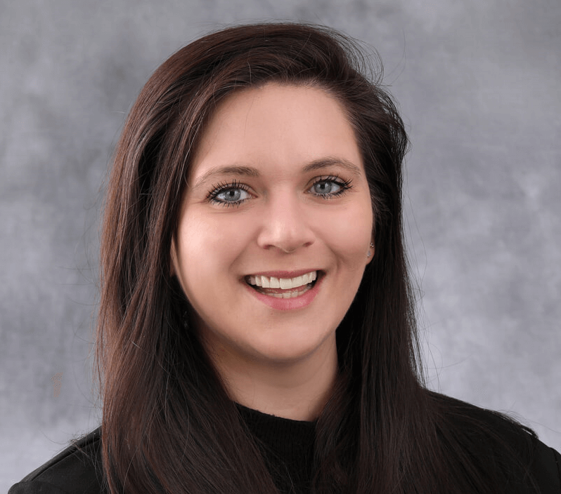 A woman with long brown hair smiles for the camera.