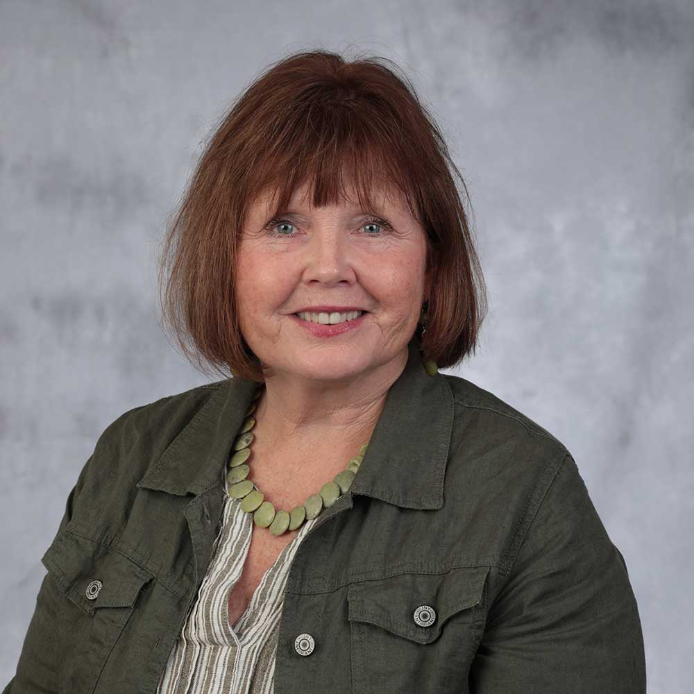 Barbara James wearing a brown jacket and smiling