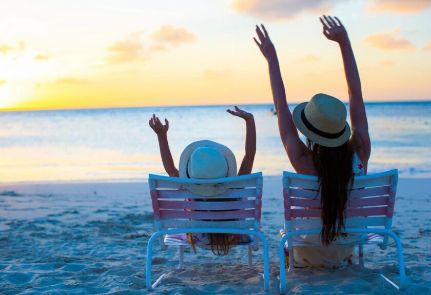 Two Woman Sitting On Chairs On The Beach