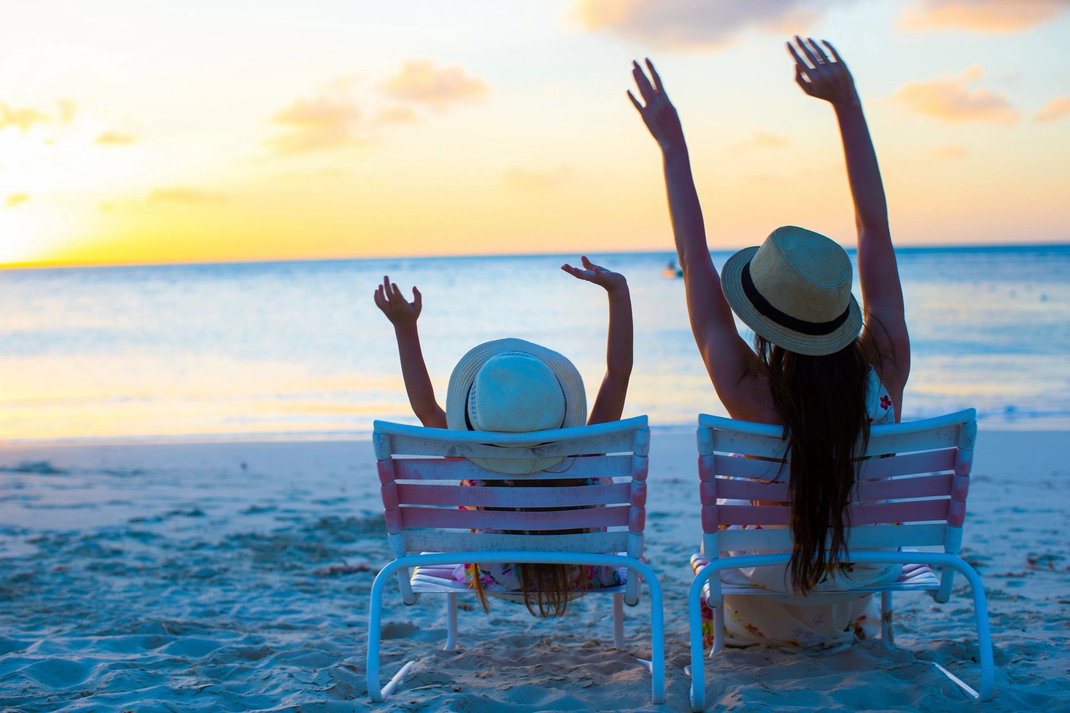 Two Woman Sitting On Chairs On The Beach