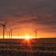 A sunset over a field with wind turbines.