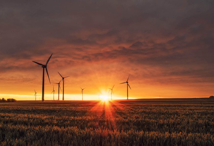 A sunset over a field with wind turbines.